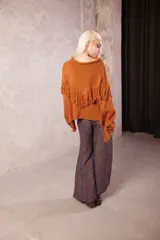 Sweater de punto color naranja, de calce holgado con cuello a la base, mangas largas y diseño intervenido con flecos en el cuerpo y en las mangas.