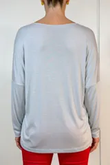 Buzo de lanilla en color gris, de corte amplio y holgado con mangas largas y cuello redondo. Presenta un diseño minimalista con terminaciones suaves al tacto.