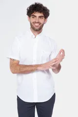 Camisa de manga corta color celeste claro, con cuello abotonado (button-down) y un bolsillo de parche en el pecho.