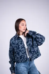 Campera corta de denim con estampado camuflado en tonos de azul, cierre frontal completo y bolsillos en el pecho.