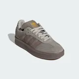 Championes Adidas modelo Samba XLG, con diseño de silueta rediseñada con mayor profundidad. Presentan exterior de cuero y gamuza en tonos gris y marrón, con las icónicas tres tiras laterales y suela de caucho robusta. Incluyen lengüeta acolchada y detalles en dorado.