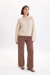 Pantalón jean ancho y elastizado en color marrón, de corte recto y tiro medio, con bolsillos y trabillas para cinto.