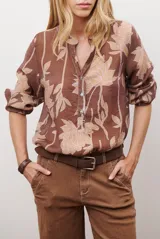 Camisa de manga larga con estampado floral en tonos marrones y negros, cuello mao y cierre frontal parcial con botones.