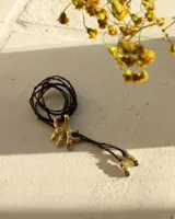 Collar con dije de bronce macizo con forma orgánica irregular, similar a un coral, suspendido de un cordón negro de seda natural anudado.