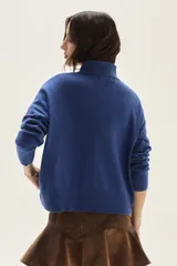 Polera de tejido de punto color azul, con cuello alto, manga larga y puños acanalados.