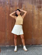 Falda corta tipo wrap de cuero color crudo, con diseño cruzado y ajuste mediante tiritas laterales.