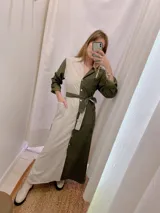 Camisola larga bicolor, con un lado en color crudo y otro en verde militar. Tiene cuello camisero, mangas largas con puños abotonados, cierre frontal con botones y lazo bicolor para ajustar en la cintura.