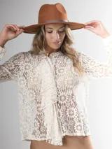 Camisa de encaje color crema, con corte clásico, volado frontal y botones al frente.