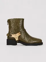 Bota corta de cuero color verde oliva, con punta cuadrada y suela de goma negra. Presenta un detalle decorativo de pieza metálica dorada con textura en el lateral y cierre trasero.