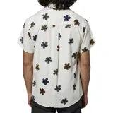 Camisa de manga corta color blanco con estampado de flores pequeñas en tonos oscuros y tierra. Presenta cuello clásico, cierre frontal con botones y un bolsillo en el pecho.