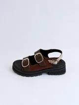Sandalias de cuero charolado bordó con punta redonda, suela flatform chunky negra con ranuras, y dos tiras frontales con grandes hebillas metálicas plateadas y una tira trasera ajustable.