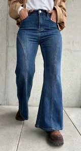 Jean de tiro alto con corte semi oxford, confeccionado en denim con elasticidad. Presenta un diseño con costuras verticales decorativas en el frente que estilizan la silueta.