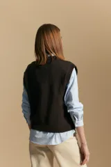 Chaleco tejido color crema con diseño de rombos calados, cuello redondo y sisas.