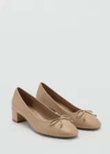 Zapato de salón color beige con tacón bloque bajo y adorno de lazo en la puntera.