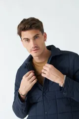 Campera azul marino de nylon capitoneada, con cuello medio y bolsillos tipo sobre con botón.
