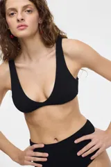 Top de bikini negro con escote en V y tirantes anchos, de tela texturizada.