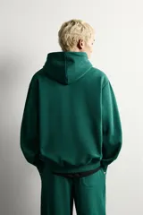 Sudadera con capucha de corte relajado, confeccionada en tejido de algodón con interior cepillado. Presenta manga larga, bolsillo frontal tipo canguro y acabados en rib en puños y bajo.