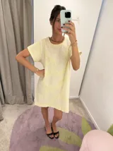 Vestido corto de corte recto y holgado, color amarillo claro con bordados artesanales en hilo amarillo. Presenta cuello redondo y mangas cortas.