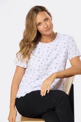 Blusa blanca de manga corta con estampado de pequeñas hojas oscuras, cuello redondo y terminación de ruedo con ondas.