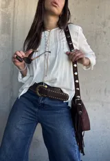 Blusa oversize de color blanco con diseño romántico y bohemio, confeccionada con detalles de encaje y botones forrados en el frente. Cuenta con mangas largas.