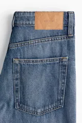 Pantalón de jean azul de tiro alto, corte ancho y largo hasta el tobillo. Confeccionado en denim de algodón rígido con cinco bolsillos, cierre frontal con cremallera y botón. 