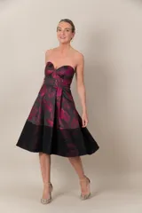 Vestido strapless negro con estampado de hojas fucsias y guarda calada negra en el bajo.