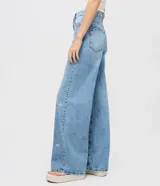 Pantalón de jean de algodón, modelo recto, con cintura mediana y trabillas. Presenta bolsillos delanteros y traseros, y un estampado localizado de flores de hibiscos.