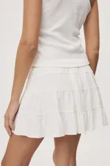 Falda corta blanca con diseño de volados escalonados y cintura elastizada, de silueta fluida y liviana.
