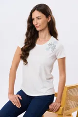 Remera blanca de manga corta y cuello redondo, confeccionada en algodón, con delicado bordado floral localizado en el hombro.