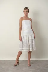 Vestido strapless color marfil con detalles de encaje y flecos.