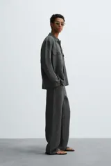 Sobrecamisa de corte relajado color gris oscuro, confeccionada en tejido de cáñamo. Cuenta con cuello de solapa, manga larga con puños abotonados, bolsillos frontales de plastrón con solapa y cierre frontal de botones.