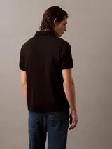 Chomba negra de manga corta con cuello polo y tapeta de tres botones. Monograma de Calvin Klein bordado en el pecho. Corte regular.