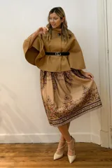 Capa corta negra de paño italiano con cuello alto y cinturón con hebilla dorada.