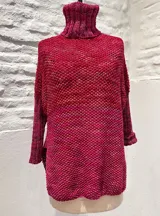 Sweater tejido a mano en lana merino color crema, con cuello alto tipo polerón y mangas largas.