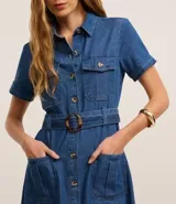 Vestido midi de jeans azul con cuello inglés, manga corta, abotonado delantero, bolsillos utilitarios y cinturón con hebilla redonda.