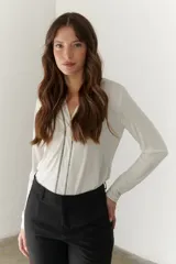 Remera color hueso de manga larga con cuello en V y costuras decorativas verticales en el frente.