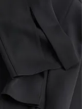 Pantalón negro de punto técnico, corte slim, pierna acampanada con aberturas traseras, talle medio, cierre de cremallera oculto y detalles de costuras verticales.