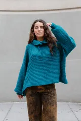 Buzo de tejido de punto en mezcla de lana y alpaca, color gris. Presenta una silueta amplia con cuello tipo polo que incluye broches para convertirlo en polera, mangas largas con puños y un diseño de tejido horizontal.