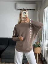 Sweater color marrón de manga murciélago oversize, con escote barco y bordado de lentejuelas y canutillos al tono en hombros y mangas.