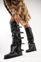 Botas altas de cuero color marrón con múltiples correas con hebillas plateadas.