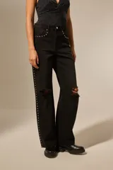 Pantalon jean negro de corte recto con roturas en las rodillas y detalle de tachas en forma de estrella a lo largo de los bolsillos delanteros y en el lateral de la pierna.