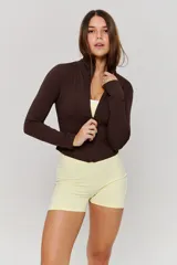 Campera deportiva de ajuste entallado, color marrón, con cuello alto, cierre frontal completo y mangas largas con aberturas para pulgares.