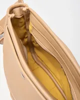 Bandolera beige de símil cuero con correa regulable y bolsillo frontal con broche a presión. Cuenta con aplique metálico con el logo de la marca en la parte inferior.