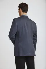Blazer de corte clásico color azul oscuro, con cierre frontal de un botón, solapas de muesca y bolsillos laterales con solapa. Presenta un bolsillo superior con pañuelo decorativo y puños con botones.