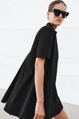 Vestido corto de algodón con cuello solapa, manga corta y cierre frontal con botones. Presenta un diseño evasé con bolsillos laterales ocultos en las costuras.