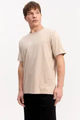 Remera de algodón color marrón con efecto gastado, de manga corta, cuello redondo y estampa tipográfica sutil al frente.