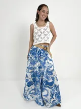 Falda larga de algodón con estampado floral en tonos azul y blanco. Tiene elástico en la cintura y viene con un cinto de rafia elastizado, desmontable.