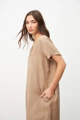 Vestido color beige de lino, corte recto, con cuello en V y mangas cortas. Tiene bolsillos laterales.