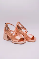 Sandalias de cuero color cobre con plataforma y taco cuadrado. Tiras cruzadas sobre el empeine y pulsera con hebilla al tobillo.