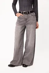 Jean wide leg de tiro medio con efecto lavado en color gris. Presenta un corte holgado de pierna ancha, cierre frontal con botón y cremallera, y bolsillos laterales. Incluye un pequeño bordado distintivo en la zona del bolsillo.